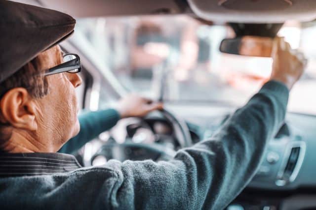 elderly-person-adjusting-mirror-before-driving