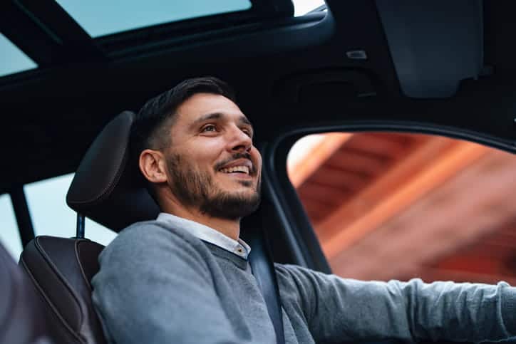 A Man Smiling As He Drives A Vehicle