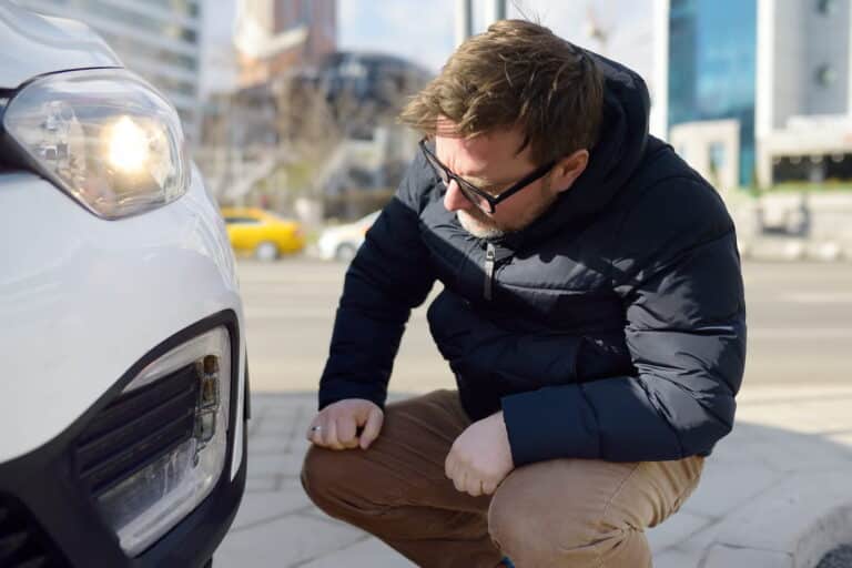 A Man Is Kneeling By The Front Of A Vehicle Inspecting For Rental Car Damage 768X512 1