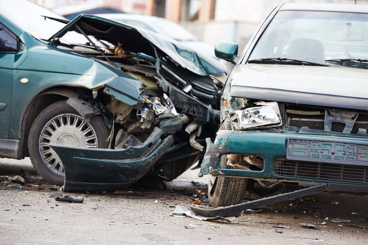 A Close-Up Of A High-Impact Car Accident Showing Significant Front-End Damage To Two Vehicles With Crumpled Hoods And Shattered Bumpers.