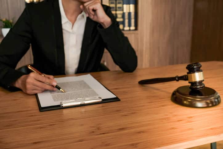 Responsabilidad De Locales En Henderson 1 Primer Plano De Una Abogada De Traje Trabajando En Documentos Legales Con Una Pluma Fuente, Junto A Un Mazo De Madera Sobre Un Escritorio De Madera.