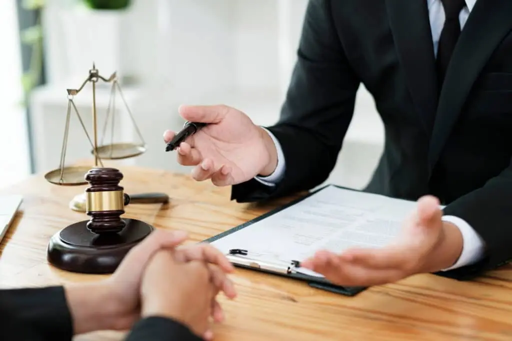Mejor Abogado De Mala Praxis Médica En Las Vegas 1 Abogado De Negligencia Médica Explicando Documentos Legales A Su Cliente En Una Mesa De Reuniones, Con Un Mazo De Juez Y Una Balanza De La Justicia Sobre El Escritorio
