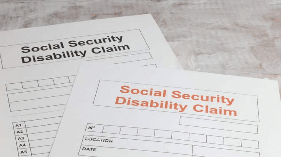 Abogados De Discapacidad Del Seguro Social En Summerlin, Las Vegas 1 Dos Formularios De Reclamación De Discapacidad Del Seguro Social Sobre Una Superficie De Madera, Uno Con El Título En Negro Y Otro En Naranja, Listos Para Ser Completados.